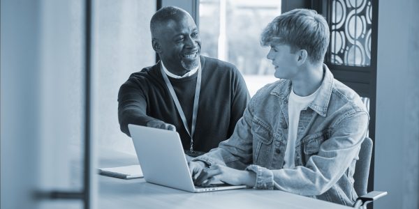 Male University Or College Student With Laptop Having Individual Meeting With Tutor