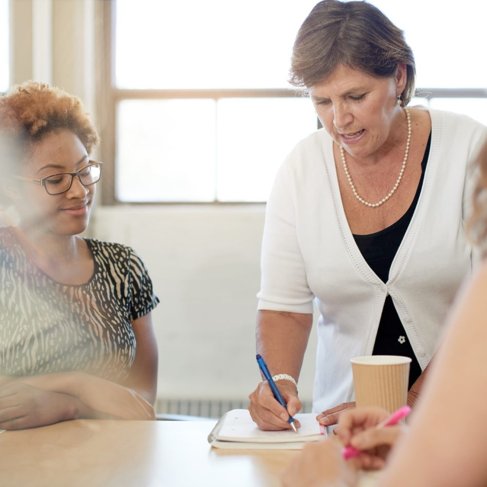 Candid picture of a female boss and business team collaborating. Filtered serie with light flares, bokeh, warm sunny tones.