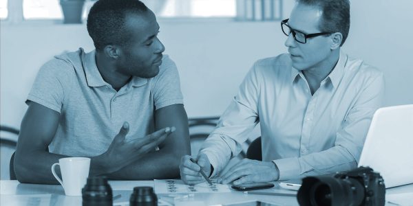 Working on creative project together. Two confident business people in casual wear sitting together at the table and discussing something